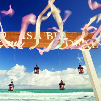 Свадебный декор на пляже с фонариками и развевающимися лентами на фоне моря