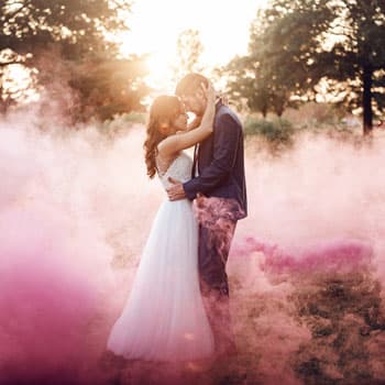 Жених и невеста на свадебной фотосессии в Минске в клубах розового дыма на закате