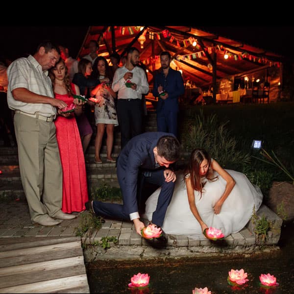 Молодожёны и гости запускают светящиеся лодочки на воде в честь завершения свадьбы в Минске
