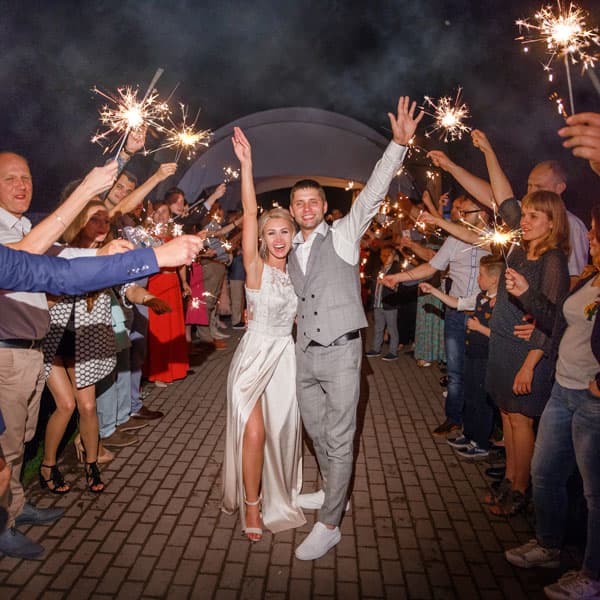 Молодожёны проходят сквозь коридор из бенгальских огней, зажжённых гостями на свадьбе в Минске