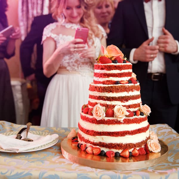 Молодожёны и гости на торжественном разрезании многоярусного свадебного торта с ягодами на свадьбе в Минске