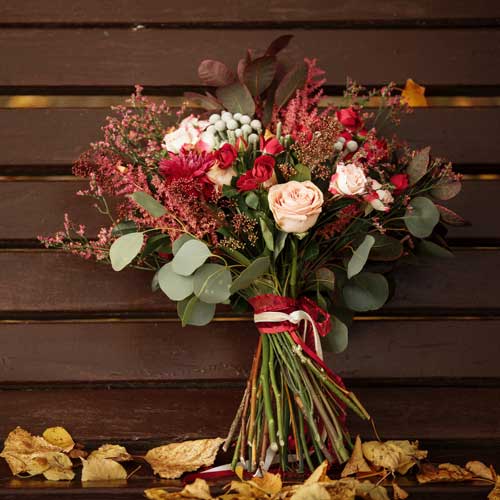 Осенний свадебный букет с розами и ягодами на фоне деревянной стены в Минске
