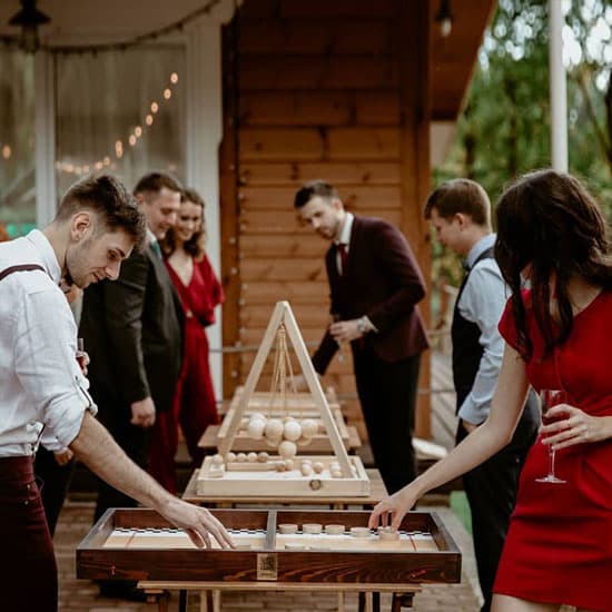 Гости на свадьбе играют в настольные игры на свежем воздухе, создавая атмосферу радости и непринуждённости